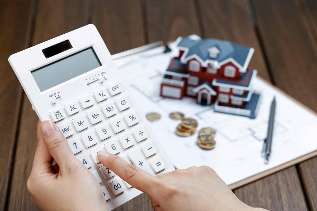 female-hand-operating-calculator-front-villa-house